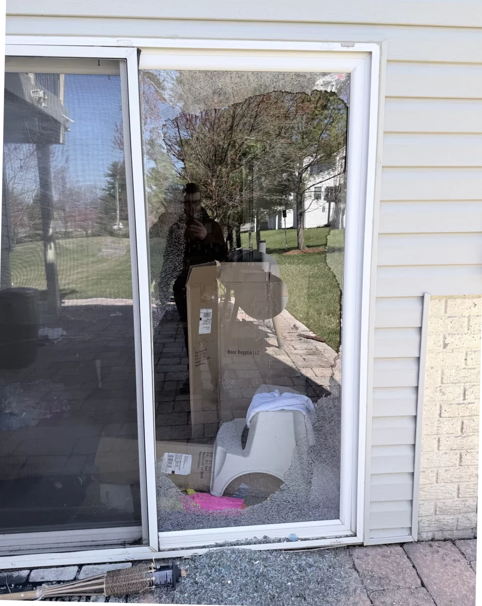 Broken sliding glass door with shattered glass on the ground