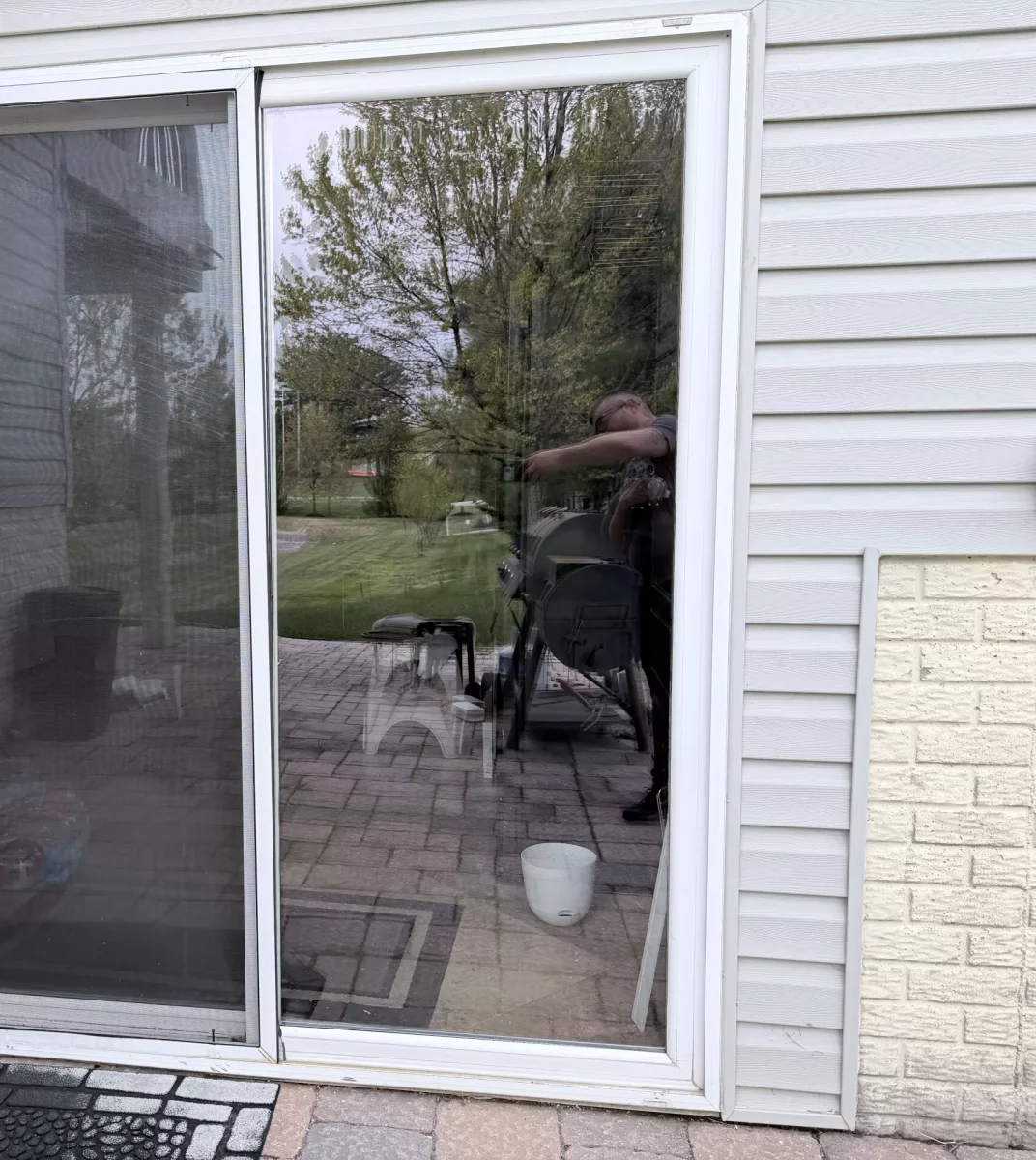 Exterior view of a residential sliding glass patio door with screen