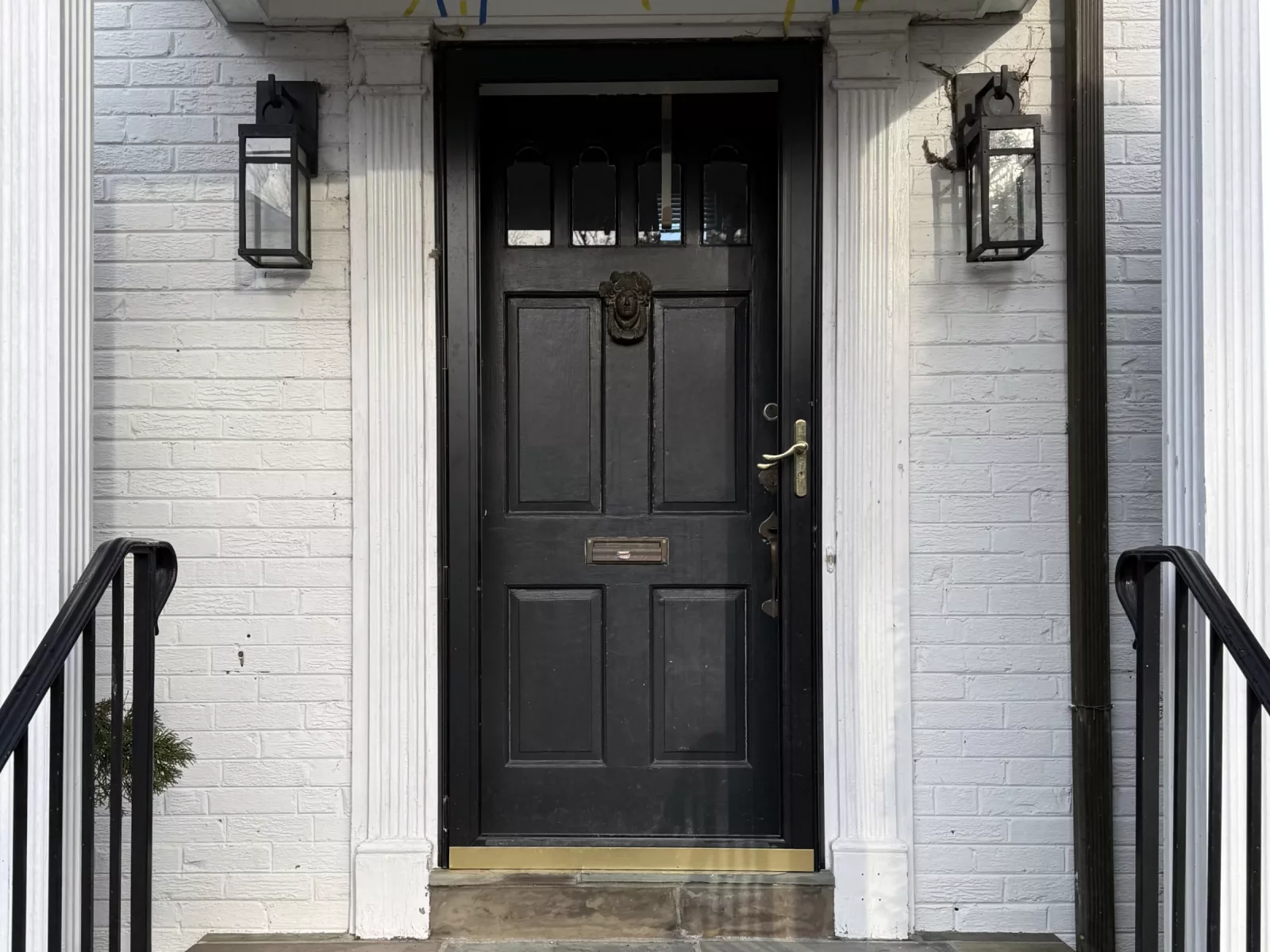 Black entry door with sidelights and stone steps at house entrance