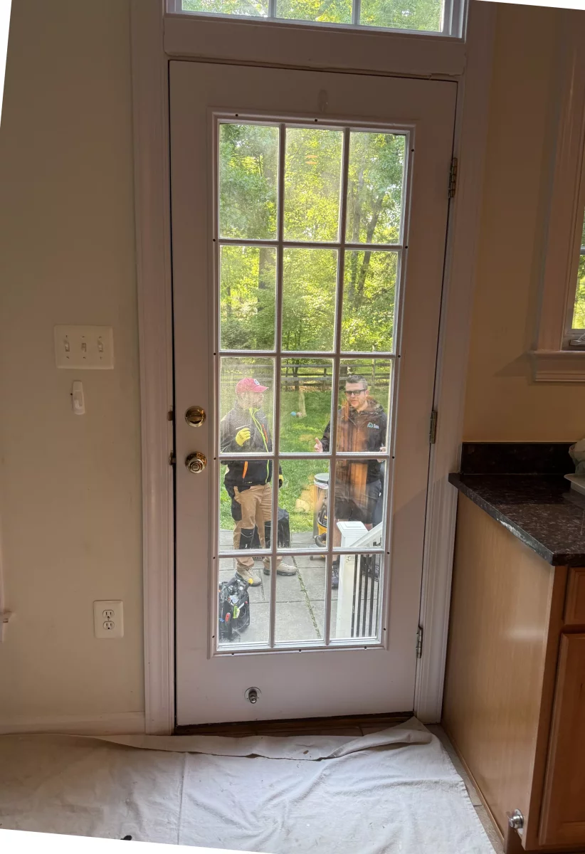 Interior view of a glass door with workers and tools outside