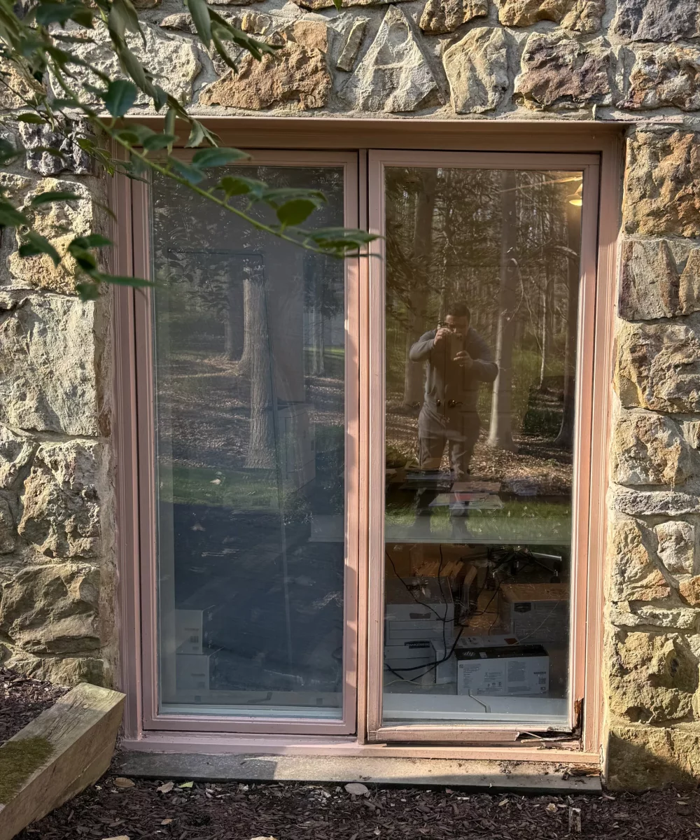 Exterior stone wall with sliding glass door showing visible rot at the bottom