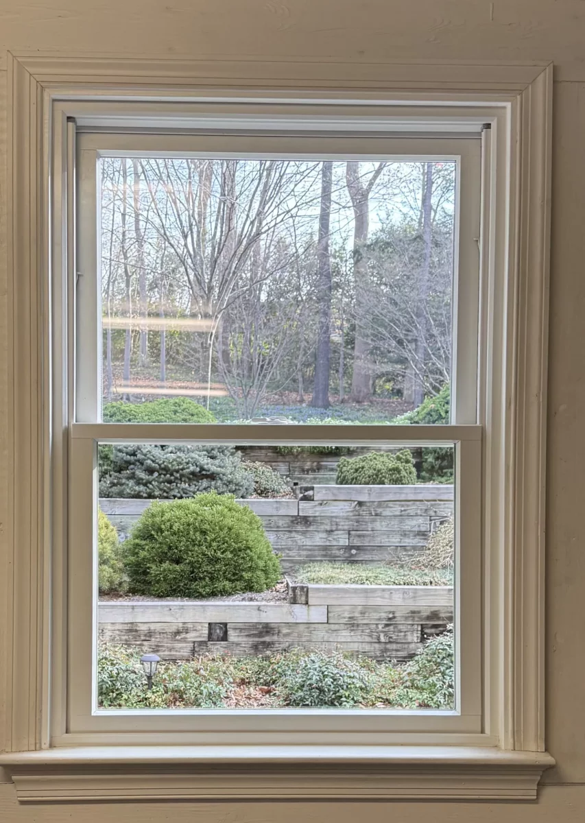 Interior view of a single window with white trim in a painted block wall
