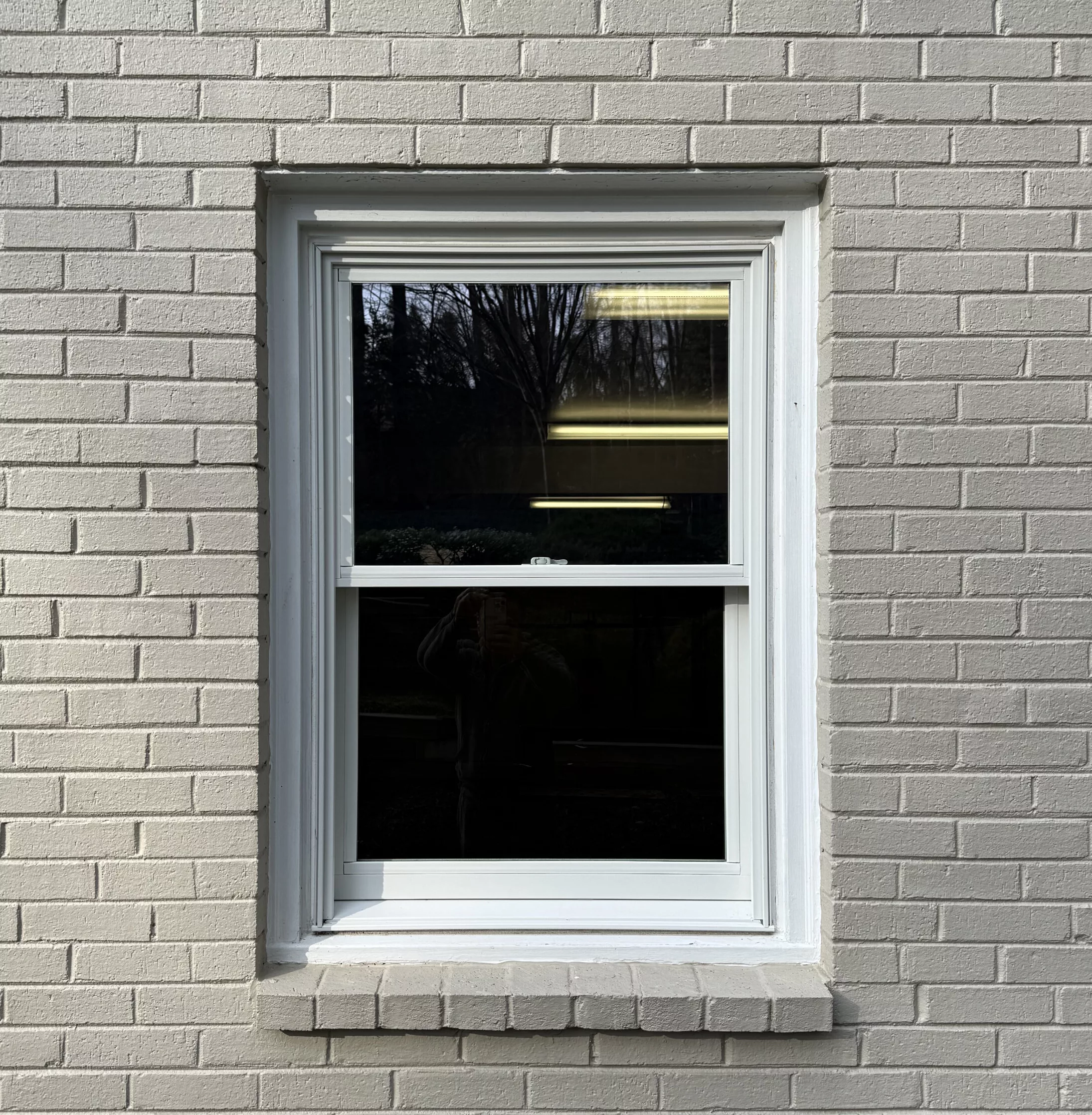 White framed window installed in painted brick exterior wall