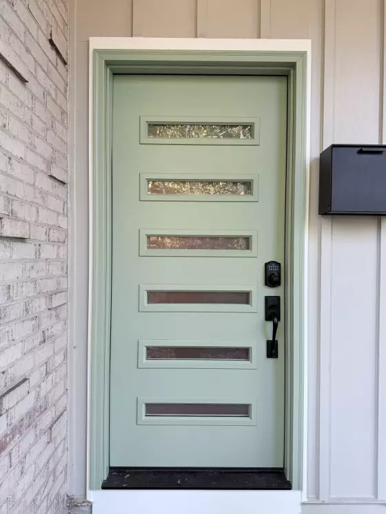 Green entry door with horizontal glass panels and black handle