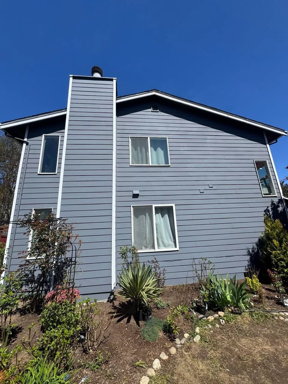 Completed gray siding and exterior repaint on an Everett, WA home with landscaped front yard